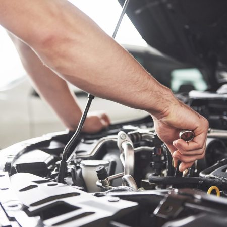 Close up hands of unrecognizable mechanic doing car service and maintenance.